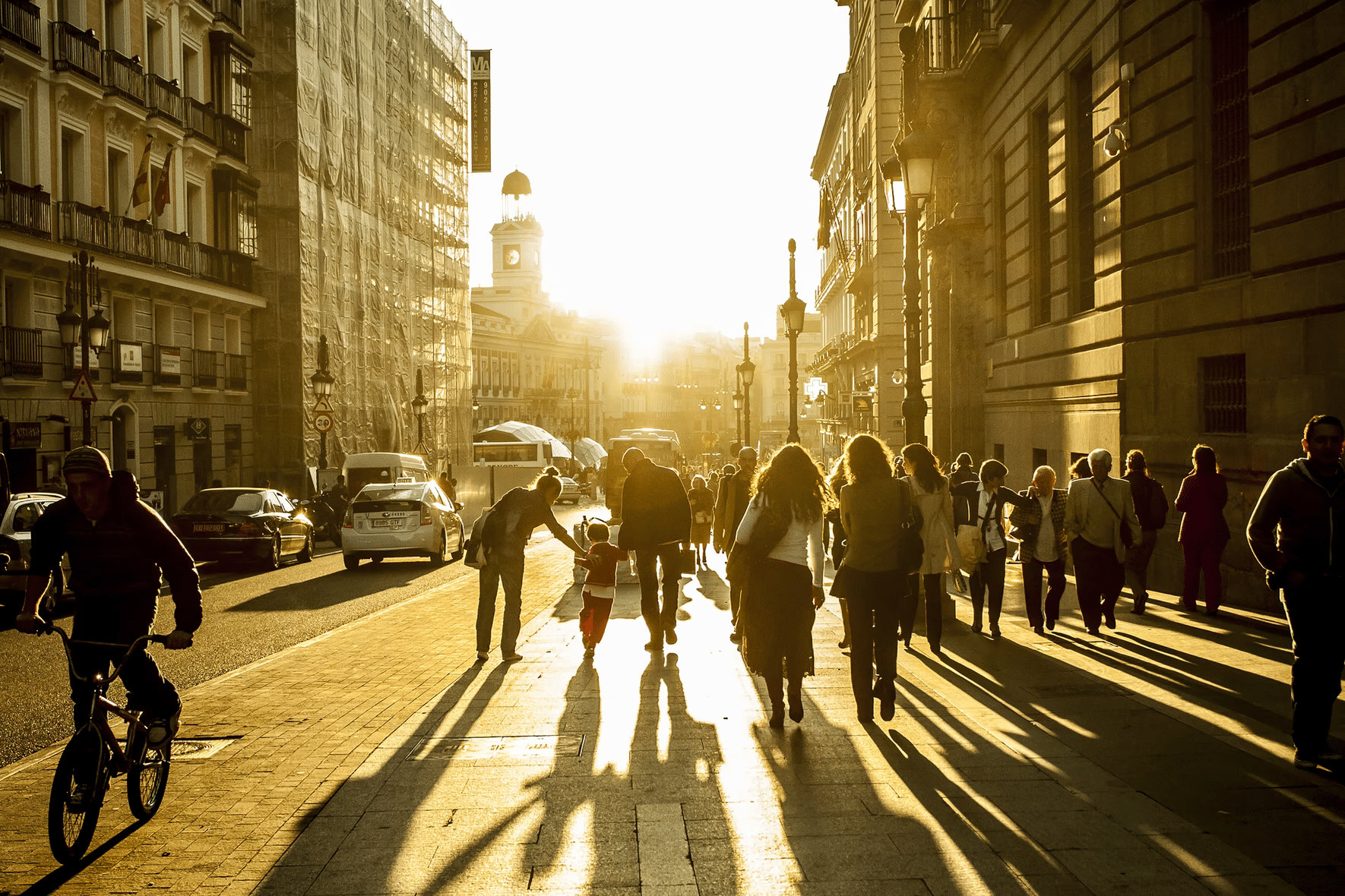 people walking on a big street towards the sun seen from the back