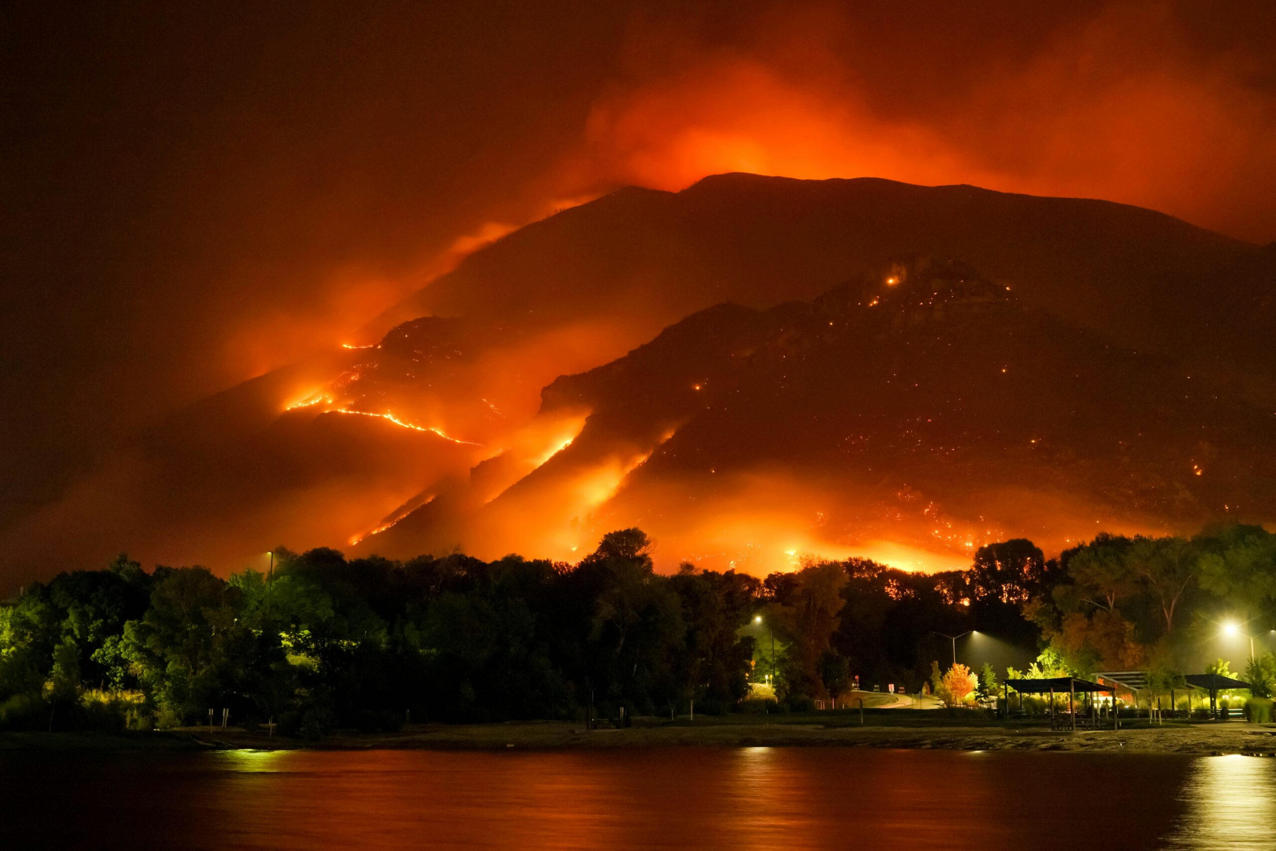 Waterfront homes in front of a backdrop of raging wildfires due to climate change