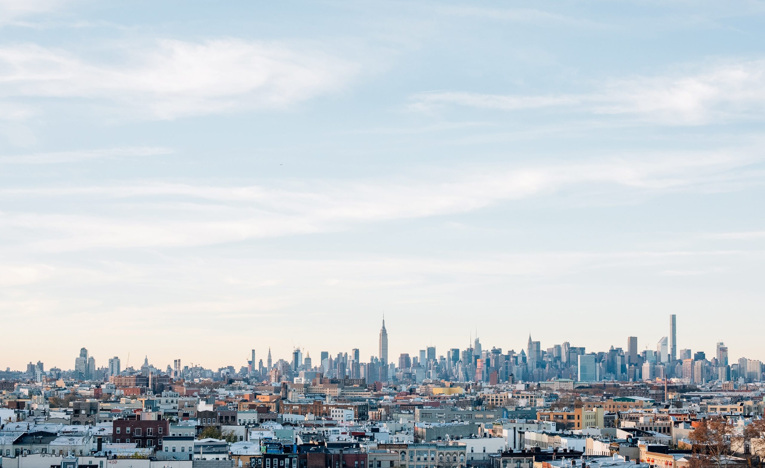 Skyline of tall buildings in houses against a clear blue sky in Brooklyn